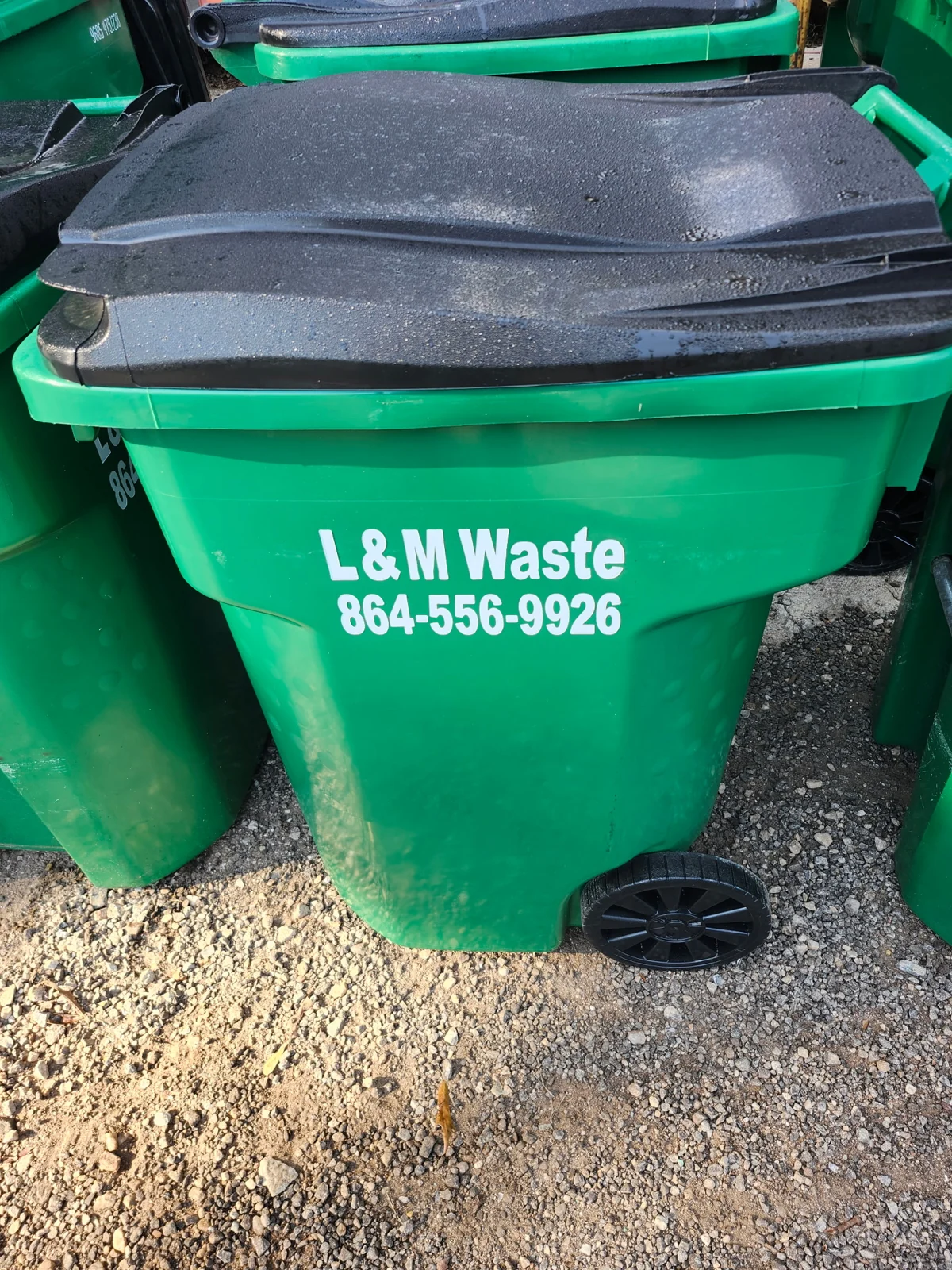 Green L&M Waste Management trash cart with a black lid
